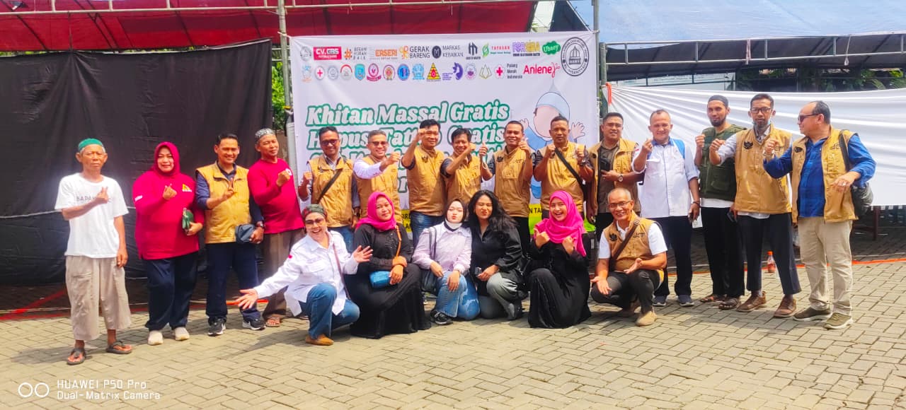 Tim gabungan petugas kesehatan, relawan Sister Sehaty, dan panitia berfoto bersama di lokasi Bakti Sosial Desa Pasir Bolang. Terlihat beberapa anggota tim mengenakan rompi cokelat bertuliskan "Gerak Bareng" dan rompi biru, berlatar belakang banner utama kegiatan "Khitan Massal Gratis Hapus Tatto Gratis".
